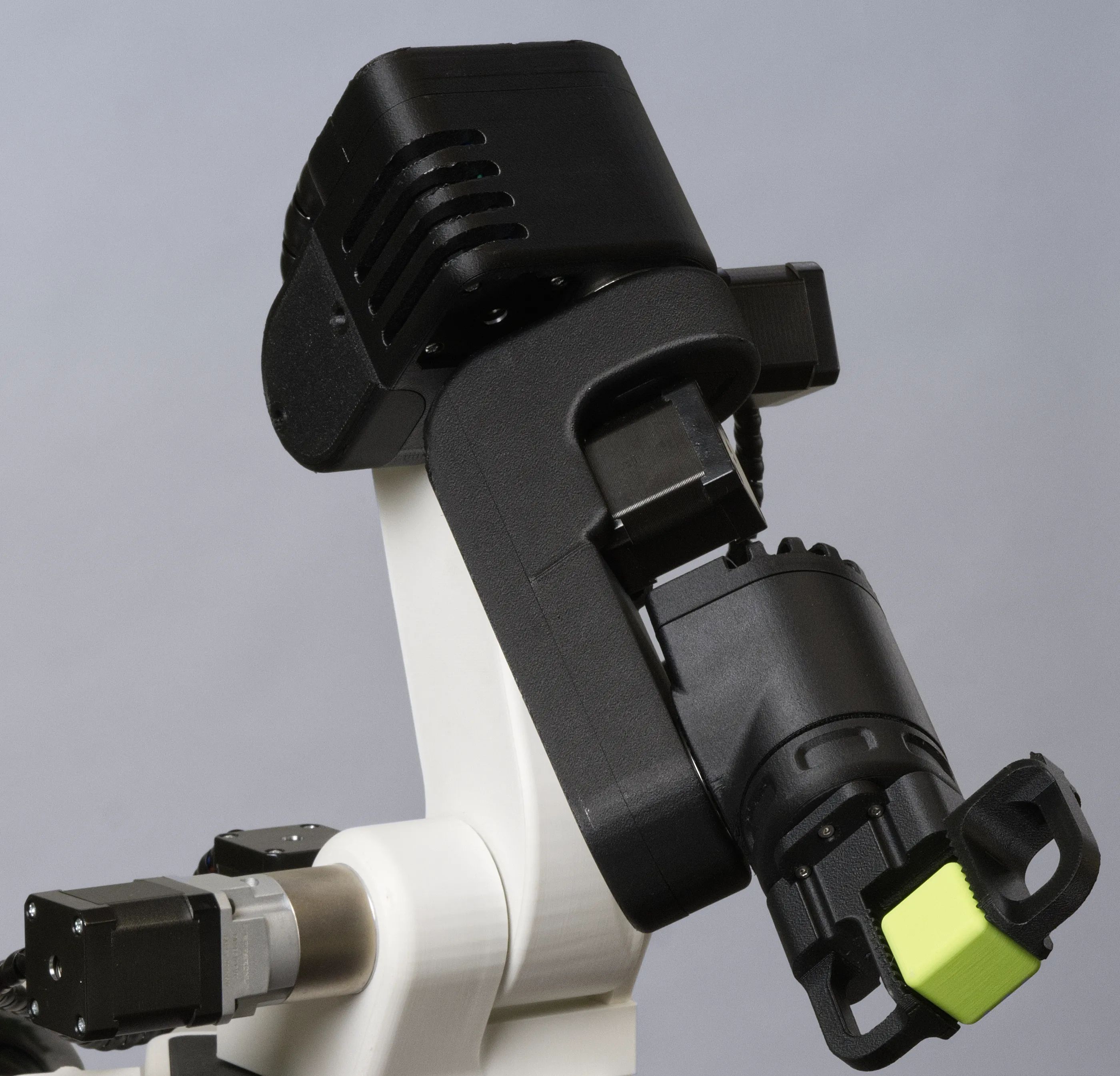 A photo of the 3D-printed robot robot with gripper and a plastic cube moving to the right.