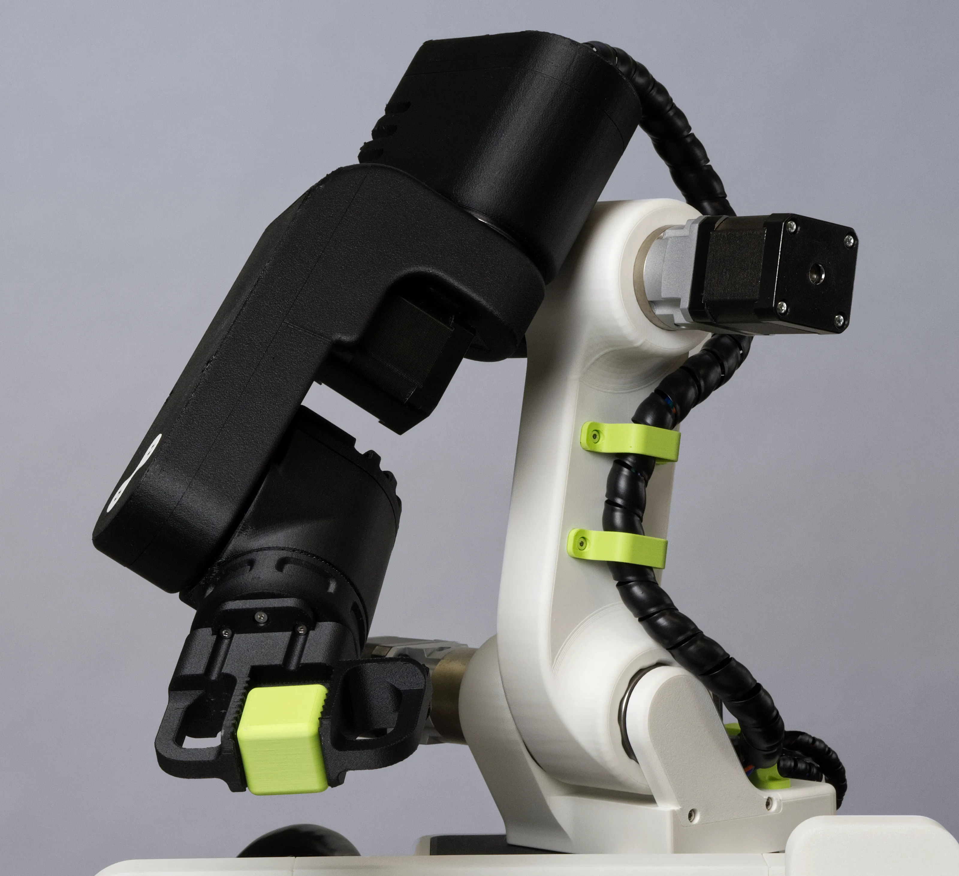 A photo of the 3D-printed robot robot with gripper and a plastic cube moving to the left.